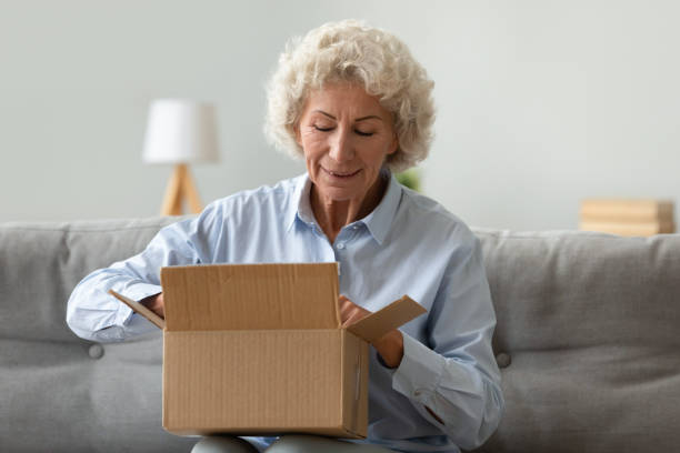 istock Happy elderly woman open parcel shopping online 1226286161