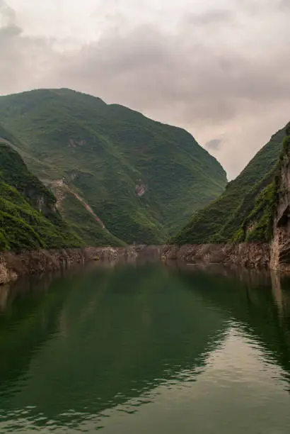 Guandukou, Hubei, China - May 7, 2010: Wu Gorge in Yangtze River: narrow stretch of green water canyon with green foliage covered mountain slopes on both sides under cloudscape.
