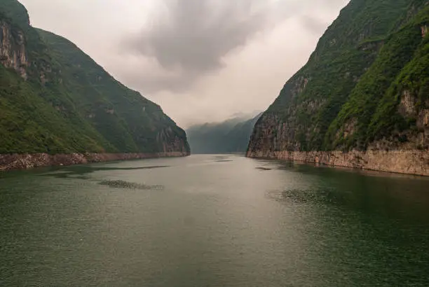 Guandukou, Hubei, China - May 7, 2010: Wu Gorge in Yangtze River: the wide canyon filled with emerald green water between green forested covered mountains, and under heavy cloudscape.