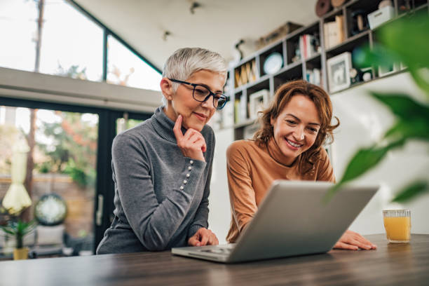 two casual women looking at laptop indoors, portrait. - laptop mature adult senior adult old imagens e fotografias de stock