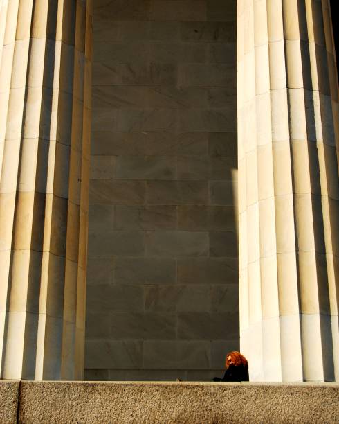 Person sitting next to one of two large pillars.