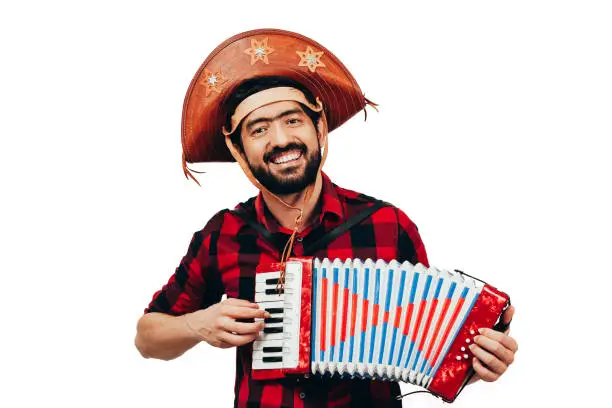 Photo of Brazilian man wearing traditional clothes for Festa Junina - June festival - playing accordion