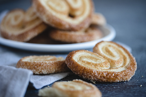 Palmier Puff Pastry. Delicious french palmier cookies with sugar on a white plate on dark background.