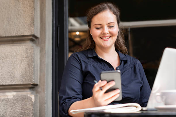 istock Happy Plus Size Woman Sitting in a Cafe and Using her Smartphone 1226301129