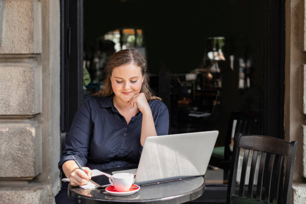 istock Beautiful Plus Size Woman Sitting in a Cafe and Working on her Laptop Computer 1226301131