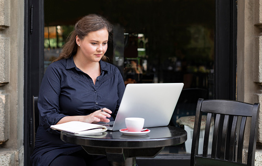 Women in business: a young female entrepreneur sitting in a coffee shop and using her pc.