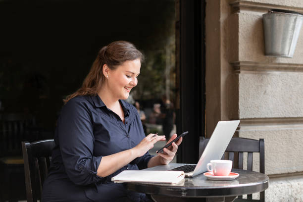 istock Happy Plus Size Woman Sitting in a Cafe and Using her Smartphone 1226301151