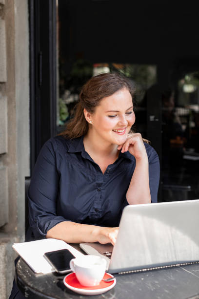 istock Beautiful Plus Size Woman Sitting in a Cafe and Working on her Laptop Computer 1226301157
