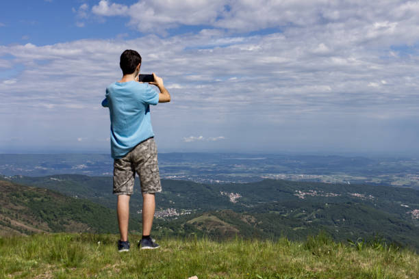 Piedmont, Italy - 2020: a guy takes a picture with his cell phone from a vantage point