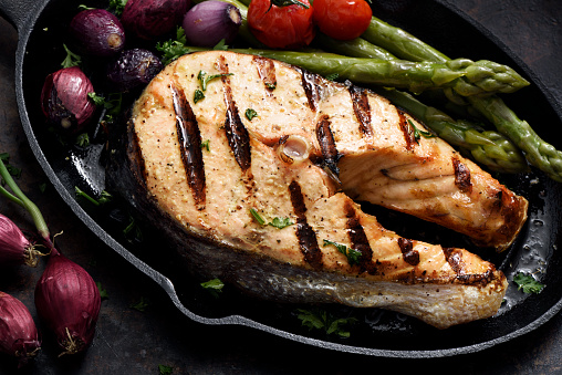 Barbecue grilled salmon steak with vegetables in a skillet