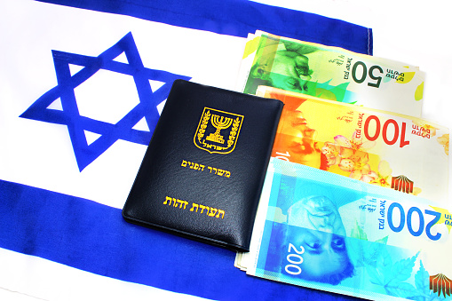 Passport Israel, Israeli shekel (currency ILS ) and IsraelI flag (passport booklet, translate from the Hebrew and Arabic :Ministry of Interior, ID). Concept: economy, business, citizenship.