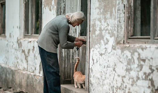 Senior woman with her cat opening front doors