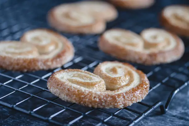 Photo of Delicious french palmier cookies with sugar in cooling rack grid