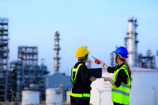 duas engenheiras inteligentes discutem juntas na fábrica da indústria de refinarias na área do centro fabril da indústria. conceito de engenharia - petrochemical refinery - fotografias e filmes do acervo