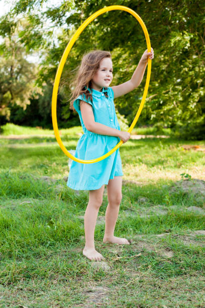 istock Child playing with hula hoop and training her skills in summer. Cheerful Exercise Concept . happy girl having fun with hula hoops outdoor. activity for the baby concept 1226323224