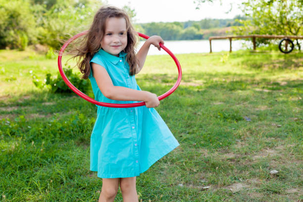 istock Child playing with hula hoop and training her skills in summer. Cheerful Exercise Concept . happy girl having fun with hula hoops outdoor. activity for the baby concept 1226323225