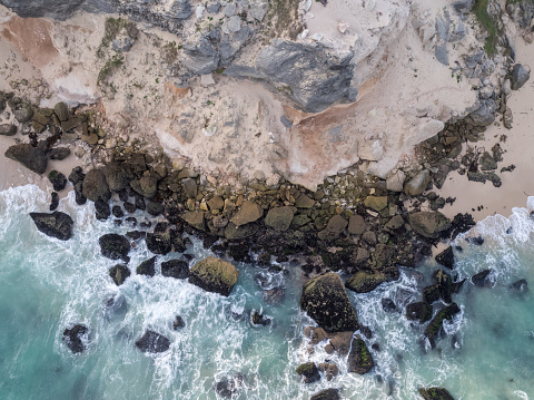 Aerial image directly above a rocky coastline. Waves break against an eroded coastline near Cape Town, South Africa