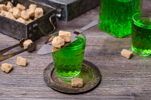 Green liquid in a glass Green liquid in a glass with sugar cubes on a dark wooden background. Selective focus. absinthe spoon stock pictures, royalty-free photos & images