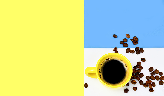 yellow cup of coffee they are natural coffee beans a variety of creative yellow-white, blue backgrounds. The concept of morning coffee, breakfast.Copy space. top view.