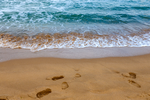 Footprints in the sand with the blue sea and dunes in the background. High quality photo