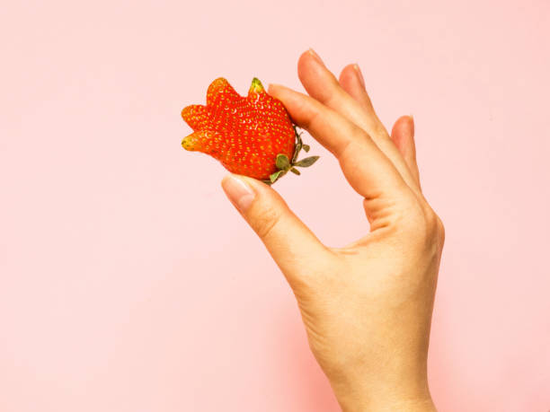 醜い食べ物:女性の手に珍しいイチゴ - deformed ストックフォトと画像