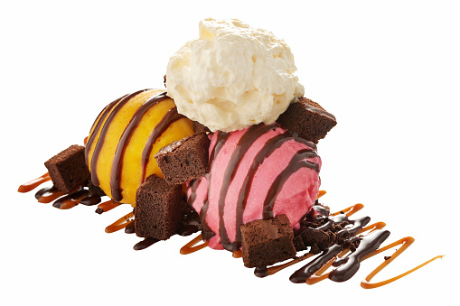 An isolated image of ice cream scoops, brownie bites, caramel sauce, chocolate sauce and whip cream.