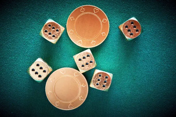 Photo of Rolling casino dice on the green poker table in the las vegas with golden chips on the table. Thrown jackpot with number six on all five dices. Entertainment and nightlife in vegas. Background