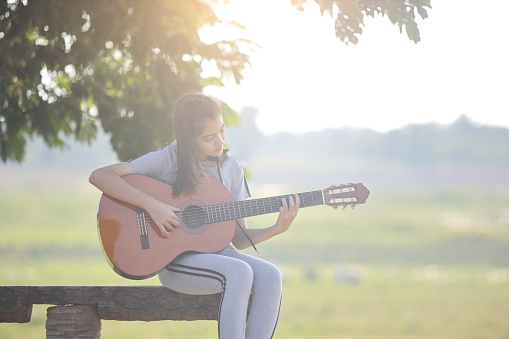 Asian kids play guitar in park