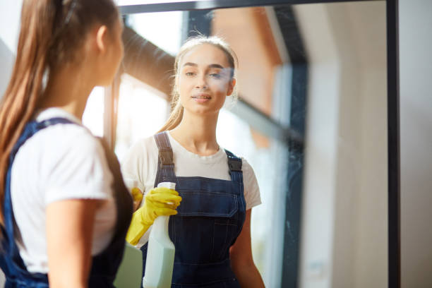 istock Young woman as professional cleaner in uniform cleaning mirror 1226346643