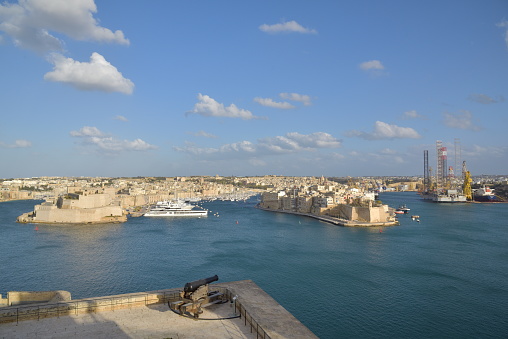 Panoramic view of Valetta harbor from high place with old gun at the foreground