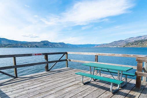 View of picnic table on wharf with view of Okanagan Lake, at Naramata Wharf Park in the Okanagan Valley, British Columbia, Canada
