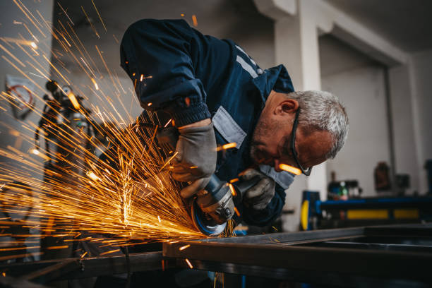 ワークショップで電動グラインダーを使用したシニアマン - circular saw flash ストックフォトと画像