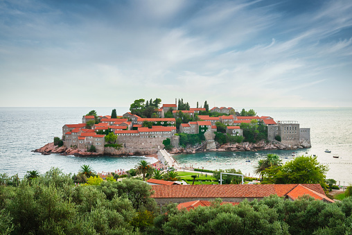 Scenic view to Sveti Stefan - Saint Stephen, Old Town built in 15th century on small islet connected to the Adriatic Coast in Sunset Twilight. Sveti Stefan, Montenegro, Southeastern Europe