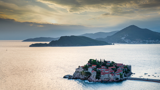 Sunset Panorama of Sveti Stefan - Saint Stephen, Old Town built in 15th century on small islet connected to the Adriatic Coast in Sunset Twilight. Sveti Stefan, Montenegro, Southeastern Europe