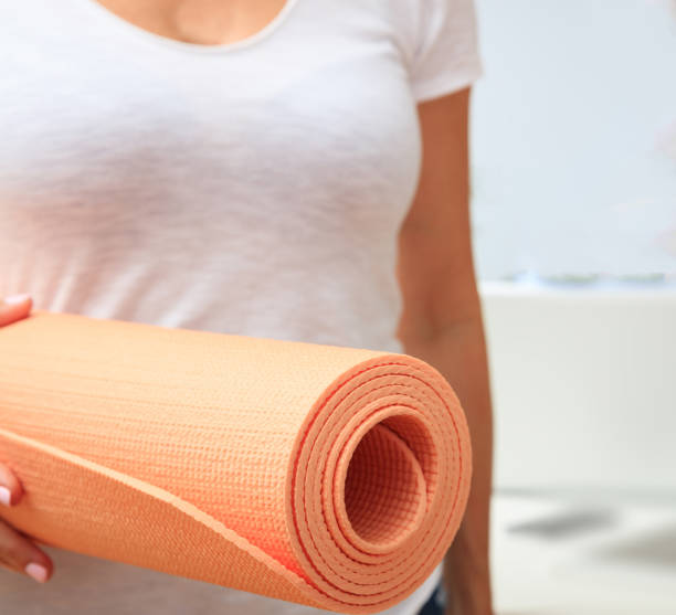 istock Woman holding an exercise mat, blur white background 1226362909