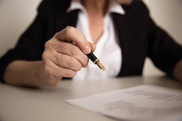 istock Female office worker writing on paper documents by pen. 1226368485