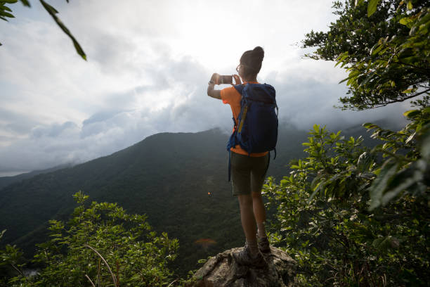 istock Successful hiker using smartphone on sunrise mountain top cliff edge 1226373629