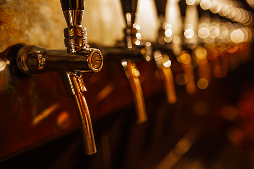 Details of the beer bar. Beer taps in a row in perspective. Warm tinting, different focus.  Close up of beer Tap. Selective focus.