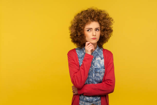 need to think! portrait of pensive woman with curly hair in casual outfit holding chin and pondering idea - pensive question mark teenager adversity imagens e fotografias de stock