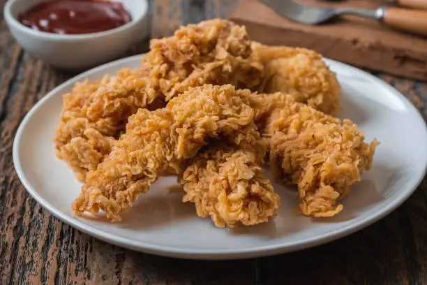 Photo of Crispy fried breaded chicken strips on plate and ketchup