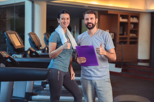 istock Personal trainer working with client in gym. Trainer man giving advises and discussing results with woman in sport club 1226379010