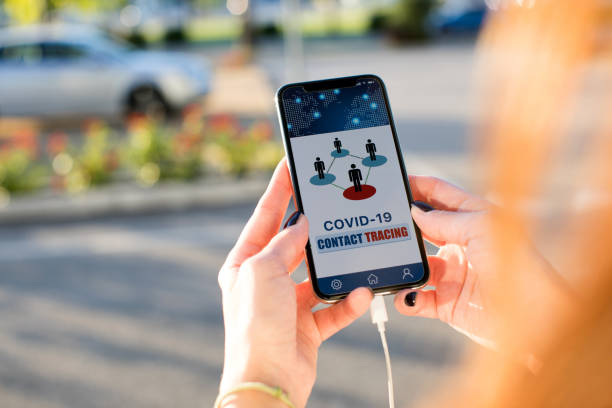 Woman holding a phone in the street using the contact tracing APP Mobile APP contact tracing adopted by national Governments to stop Covid-19 pandemic tracing stock pictures, royalty-free photos & images