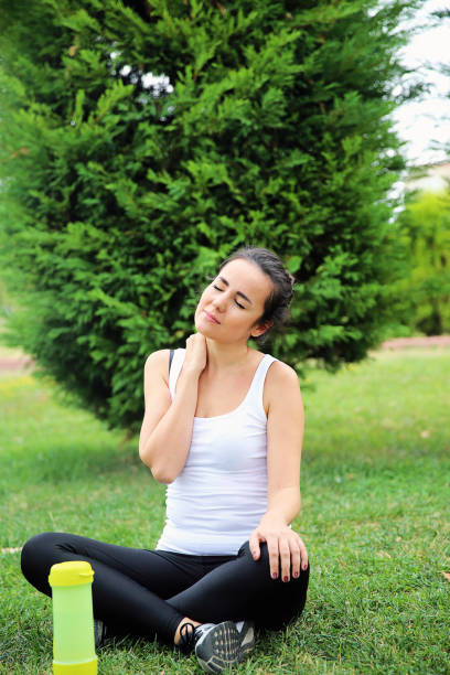 Young woman with neck pain outdoors stock photo