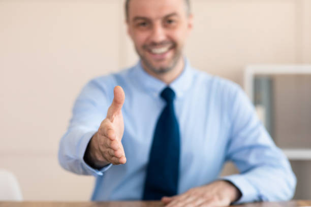 istock Businessman Stretching Hand For Handshake Greeting Sitting In Modern Office 1226383086