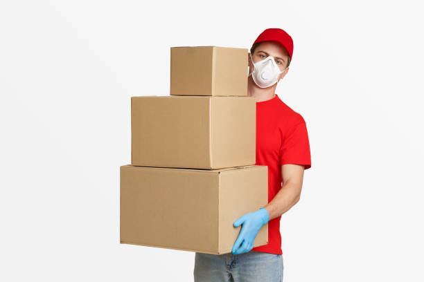 istock Postman in protective mask and gloves holds many parcels 1226383167