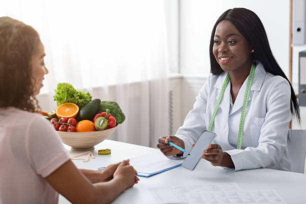 istock Cheerful dietician showing patient mobile app for counting calories 1226383771