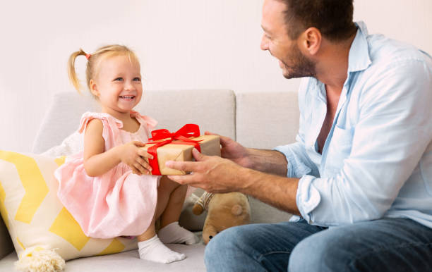 istock Excited girl holding her present sitting with dad 1226384145