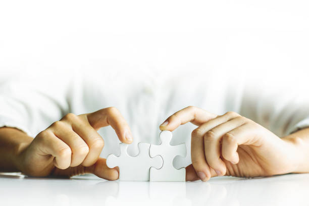 istock Hands of working woman connecting jigsaw puzzle. 1226384339