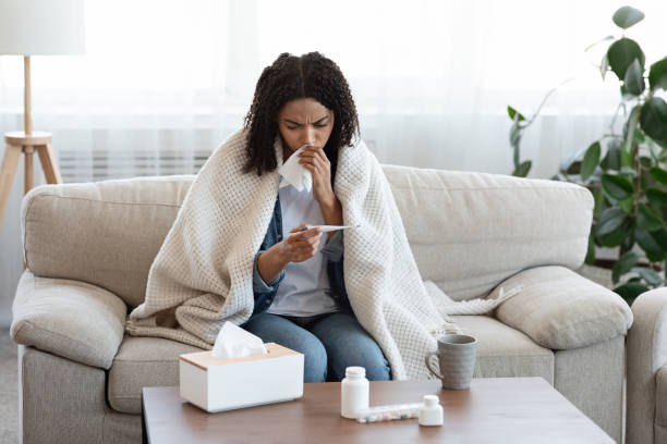 istock Flu Symptoms. Ill African Woman Checking Her Body Temperature At Home 1226384821