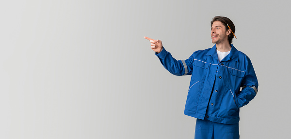 Construction Workers Hire Concept. Portrait Of Young Civil Engineer In Uniform Pointing Aside At Copy Space On Light Background